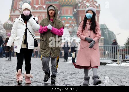 Chinese girls in protective medical masks walking on a Red square in Moscow on background of Saints Basil's Cathedral. Coronavirus protection Stock Photo