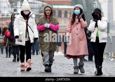 Chinese girls in protective medical masks walking on city street. Coronavirus protection Stock Photo