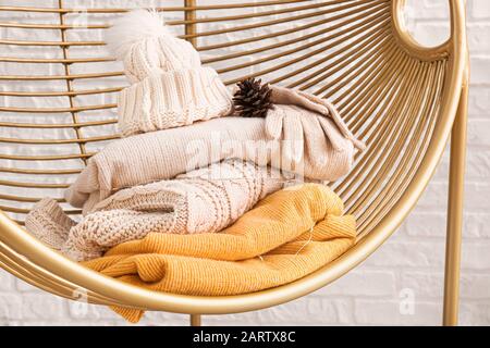 Armchair with winter clothes near white brick wall Stock Photo
