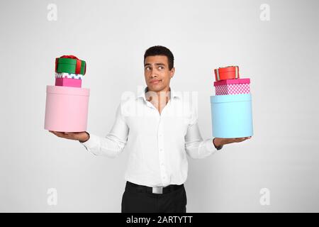 Thoughtful African-American man with gifts on white background Stock Photo