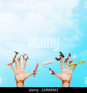 Various construction tools in hands on a blue sky background with copy space. Handyman concept Stock Photo