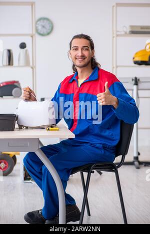 The young male contractor repairing toaster at workshop Stock Photo