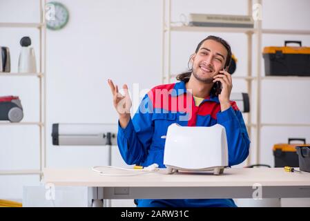 The young male contractor repairing toaster at workshop Stock Photo