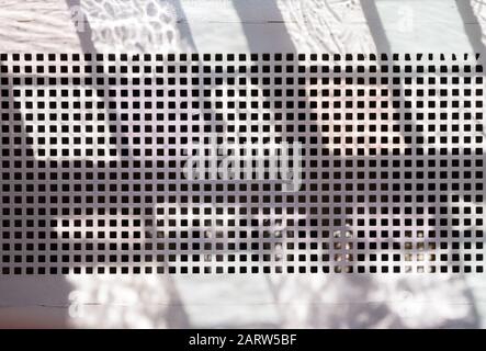 Powdered metal ventilation grille - with shadows forming a regular pattern on the background Stock Photo