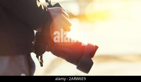 Man holds camera with hand in light sun. Concepts professional travel lifestyle photographer Stock Photo