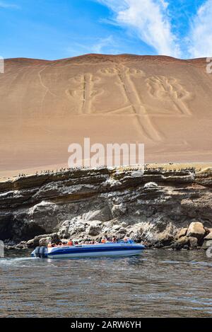 Jan 25, 2020 - Paracas, Peru: Tourists on a boat beneath the Paracas Candelabra, a prehistoric geoglyph on the Paracas Peninsula, Pisco Bay, Peru Stock Photo