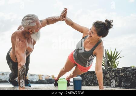 Fitness couple doing push ups exercise outdoor - Happy athletes making workout session outside - Concept of people training and bodybuilding lifestyle
