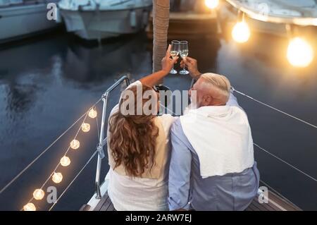 Senior couple toasting champagne on sailboat vacation - Happy mature people having fun celebrating wedding anniversary on boat trip Stock Photo