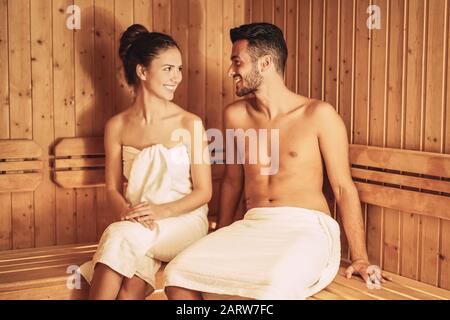 Happy couple relaxing inside sauna spa resort hotel - Romantic young lovers having relaxing day in luxury steam bath salon Stock Photo