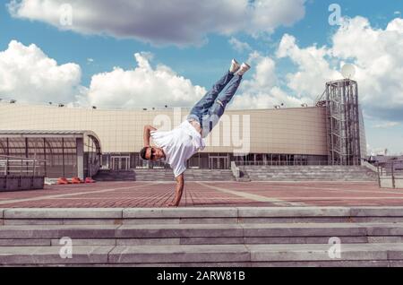 man standing on one arm, young guy dancer, summer city, dancing street dances, break of movement, modern youth style. Fashion fitness sport. Free Stock Photo