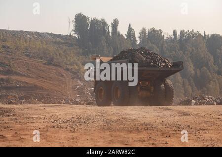 Big yellow mining truck laden anthracite moves open pit coal mine Stock Photo