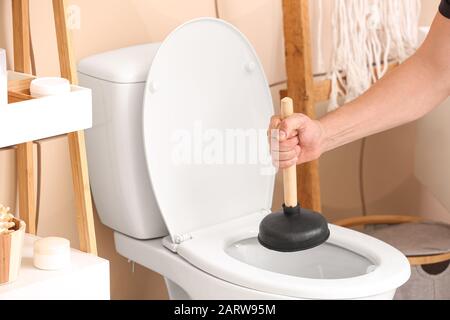 Man using plunger to unclog a toilet bowl Stock Photo