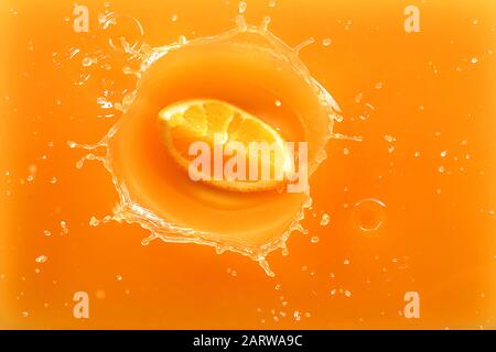 Falling of orange piece into juice, top view Stock Photo