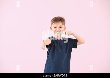 Portrait of little boy brushing teeth on color background Stock Photo