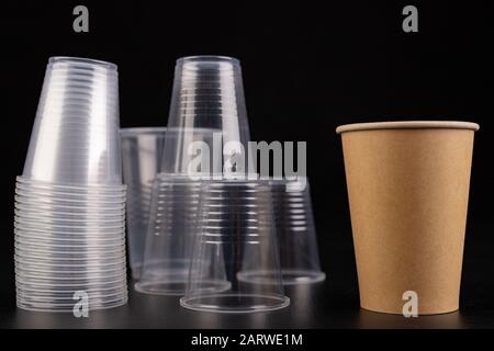 Plastic versus cardboard cups. Disposable tableware set on a table. Dark background. Stock Photo