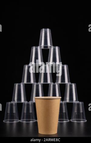 Plastic versus cardboard cups. Disposable tableware set on a table. Dark background. Stock Photo