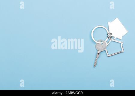 House keys with trinket on color background, top view with copy space. House key on blue background. Minimal flat lay style with place for text. Stock Photo