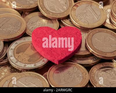 Close-up image of one and two Euro coins with red heart showing passion for money Stock Photo