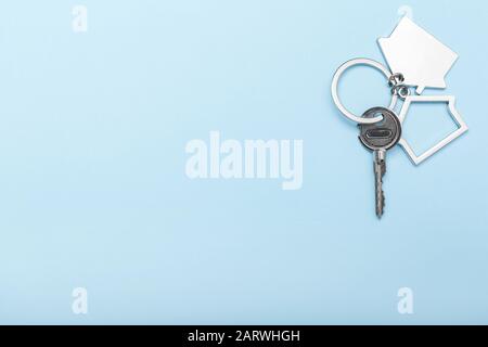 House keys with trinket on color background, top view with copy space. House key on blue background. Minimal flat lay style with place for text. Stock Photo