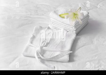 Soft clean bathrobe and towels on bed Stock Photo
