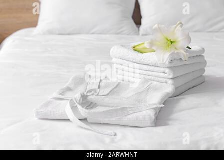Soft clean bathrobe and towels on bed Stock Photo