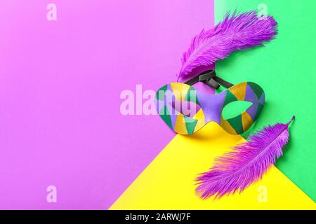 Carnival mask and feathers on color background. Celebration of Mardi Gras (Fat Tuesday) Stock Photo