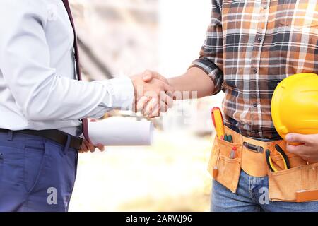 Male architect and builder shaking hands outdoors Stock Photo