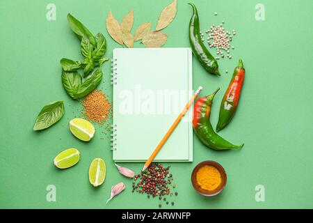 Empty notebook with different spices on color background Stock Photo