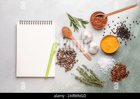 Empty notebook with different spices on light background Stock Photo