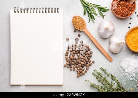 Empty notebook with different spices on light background Stock Photo