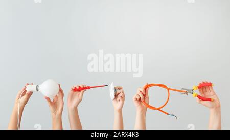 Female hands with electrician's tools on light background Stock Photo