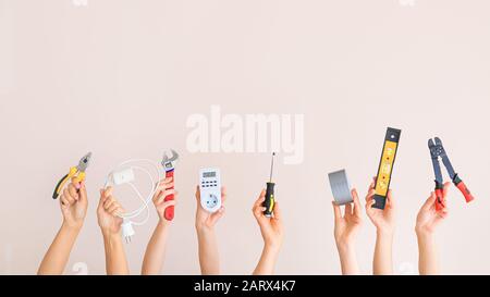 Female hands with electrician's tools on color background Stock Photo