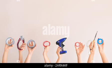 Female hands with electrician's tools on color background Stock Photo