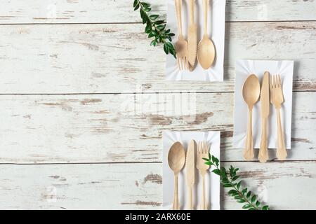 Eco friendly disposable dishes made of bamboo wood and paper on white wooden background top view. Copy space. Stock Photo