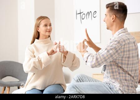 Young deaf mute couple using sign language at home Stock Photo