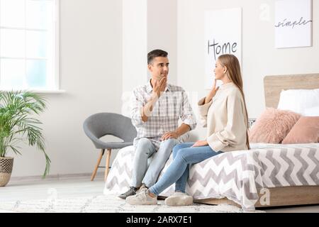 Young deaf mute couple using sign language at home Stock Photo