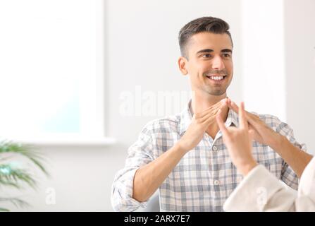 Young deaf mute couple using sign language at home Stock Photo