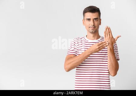 Young deaf mute man using sign language on white background Stock Photo