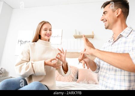 Young deaf mute couple using sign language at home Stock Photo