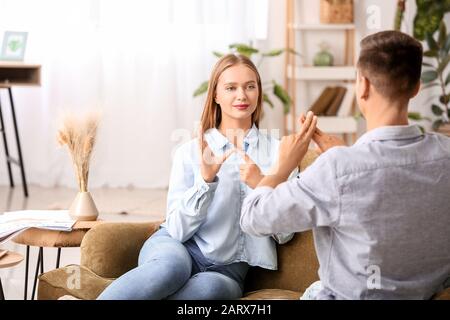 Young deaf mute couple using sign language at home Stock Photo