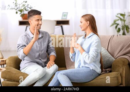 Young deaf mute couple using sign language at home Stock Photo