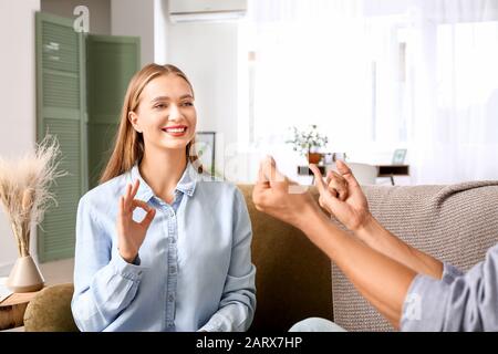 Young deaf mute couple using sign language at home Stock Photo