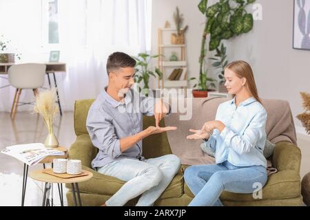 Young deaf mute couple using sign language at home Stock Photo