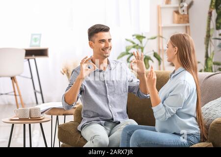 Young deaf mute couple using sign language at home Stock Photo