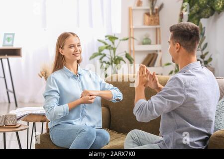 Young deaf mute couple using sign language at home Stock Photo