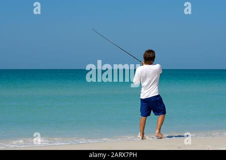 HOLMES BEACH, ANNA MARIA ISLAND, FL - May 1, 2018: A local young man on the beach fishing in the shallow water of the Gulf of Mexico. Stock Photo