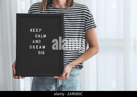 Woman holding board with motivation phrase indoors Stock Photo