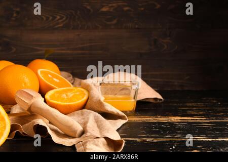 Squeezer with fresh oranges and juice on dark table Stock Photo