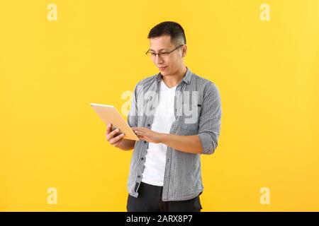 Male Asian programmer with tablet computer on color background Stock Photo