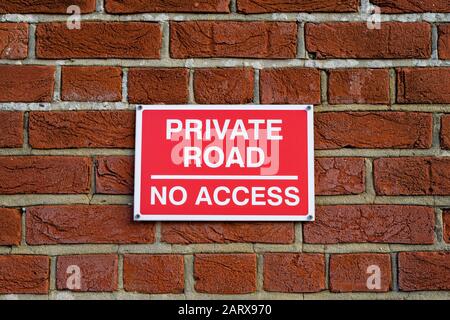 A red private road no access sign on a brick wall Stock Photo